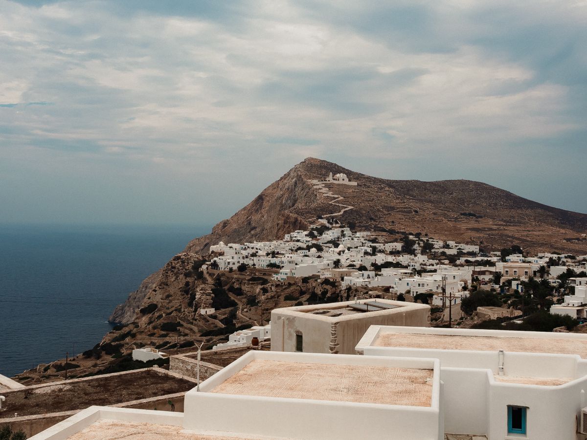 Λευκά σπίτια στη Χώρα της Φολεγάνδρου, με βραχώδη πλαγιά και θάλασσα στο βάθος· ενδεικτική φωτογραφία του νησιού, όχι των έργων διασύνδεσης.