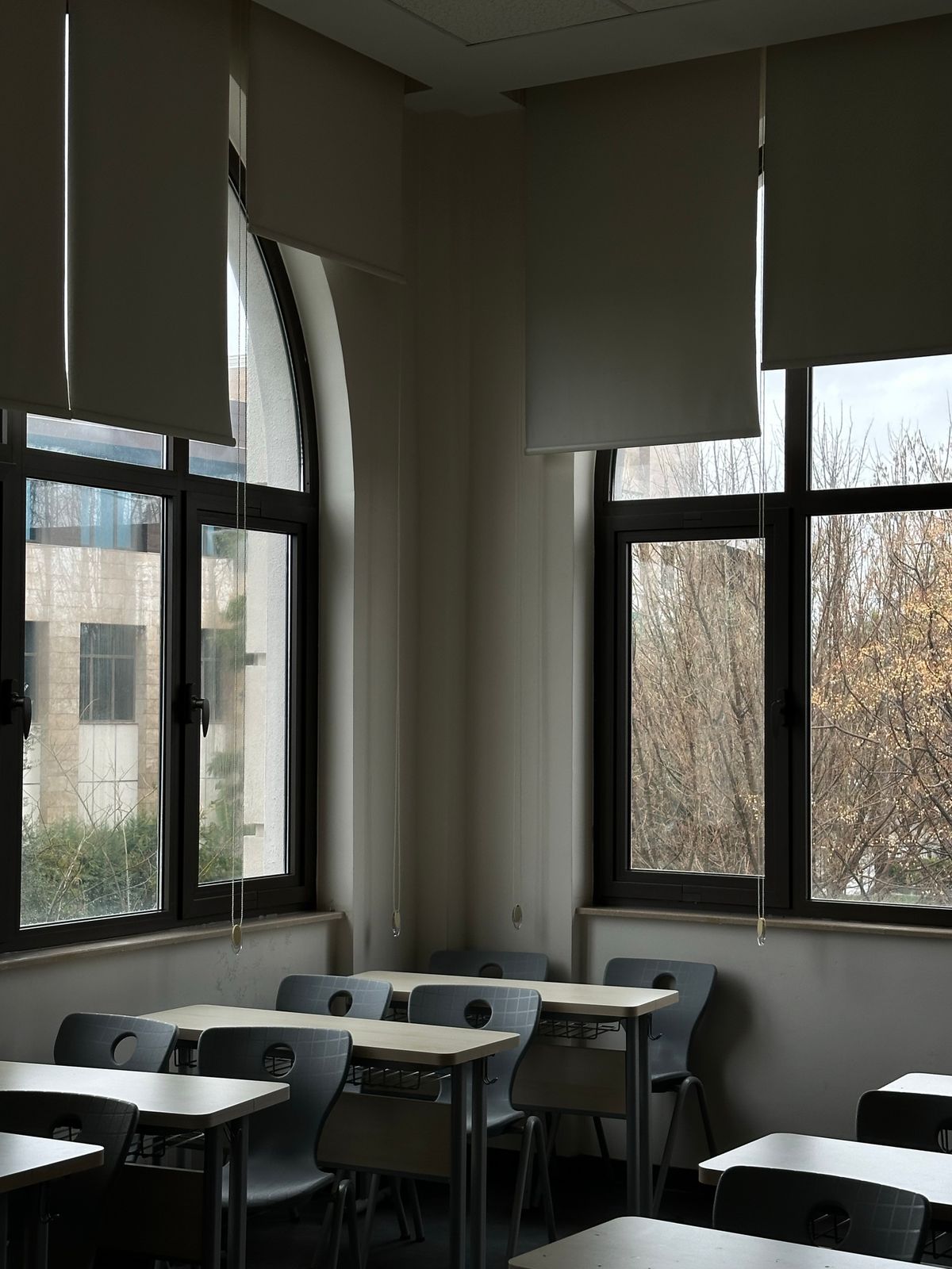 Ενδεικτική φωτογραφία άδειας αίθουσας με θρανία και μεγάλα παράθυρα· δεν απεικονίζεται το 1ο ΓΕΛ Μενεμένης.